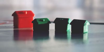 pexels photo 2855628 2855628 Close-up photo of red and green Monopoly game houses on a reflective surface.